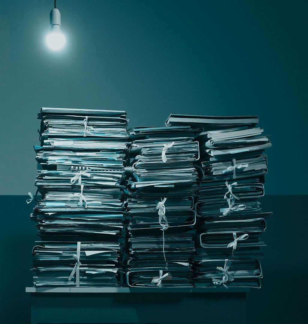 Stacks of string-tied tax documents beneath a single hanging light.